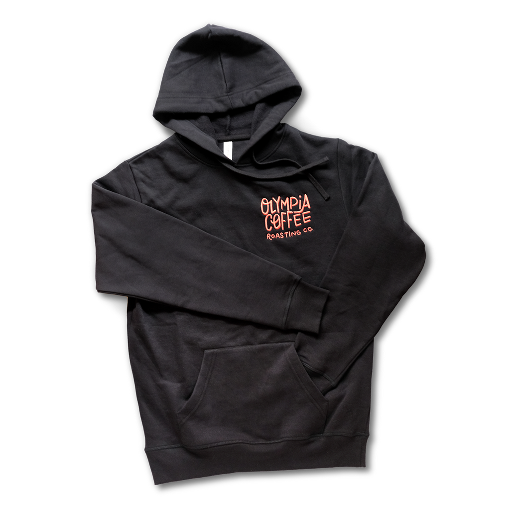 Black pullover sweatshirt hoodie with front pouch pocket. Fun, lighthearted script in orange on left chest of sweatshirt says "Olympia Coffee Roasting Co."